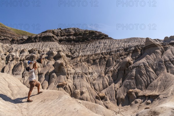 Tourist father is lifting his son in the air in the otherworldly landscape of the canadian badlands, drumheller, alberta, under the summer sun