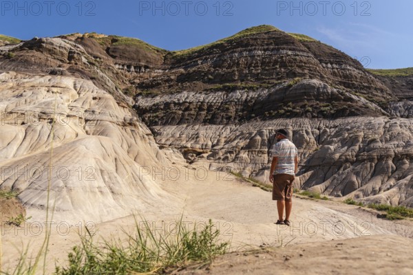 Tourist admiring the landscape of horseshoe canyon in drumheller, alberta, canada, enjoying the beautiful arid landscape under blue sky on a sunny summer day
