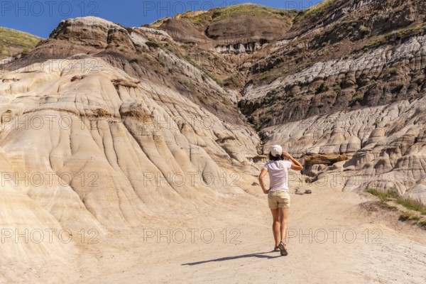 Female tourist walking and exploring horseshoe canyon in drumheller, alberta, a unique geological formation showcasing hoodoos and canyons, a popular tourist destination in the canadian badlands