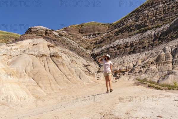 Female tourist walking through the arid and eroded landscape of drumheller valley in the canadian badlands, enjoying the sunny summer day and breathtaking geological formations