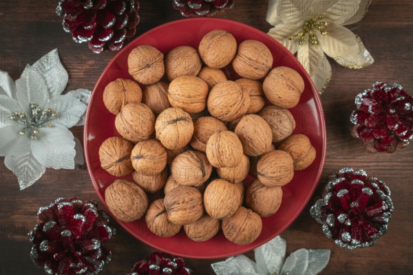 Walnuts on red plate surrounded by festive Christmas decorations