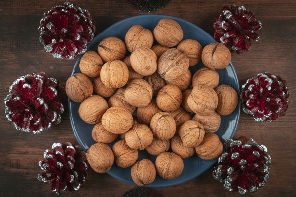 Blue plate full of walnuts surrounded by decorative cones
