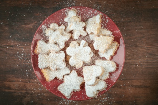 Christmas cookies with powdered sugar on red plate