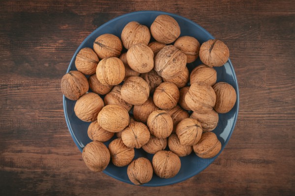 Blue plate with walnuts in the center of a wooden table