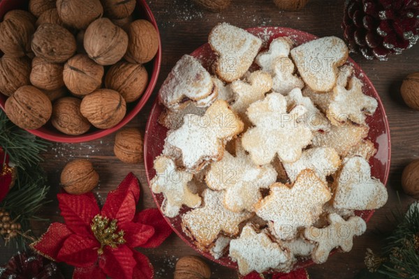 Christmas-shaped cookies on a plate next to walnuts, decorated for Christmas