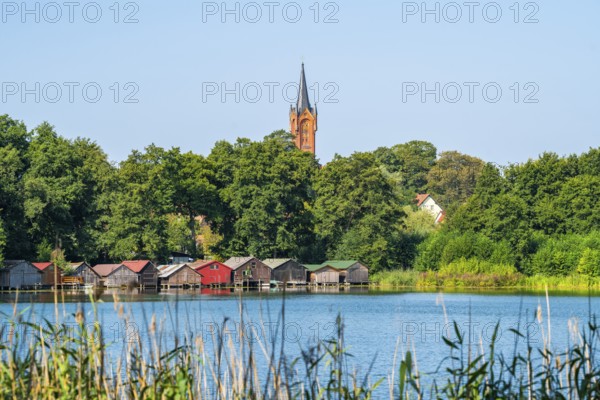 View across the Haussee to the town church and colorful boathouses on stilts, Feldberg, Feldberg Lake District, Mecklenburg-Western Pomerania, Germany