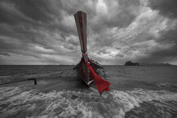 Longtail boat on the beach with dark rain clouds behind it, Koh Ngai island, Andaman Sea, Satun province, southern Thailand, Thailand