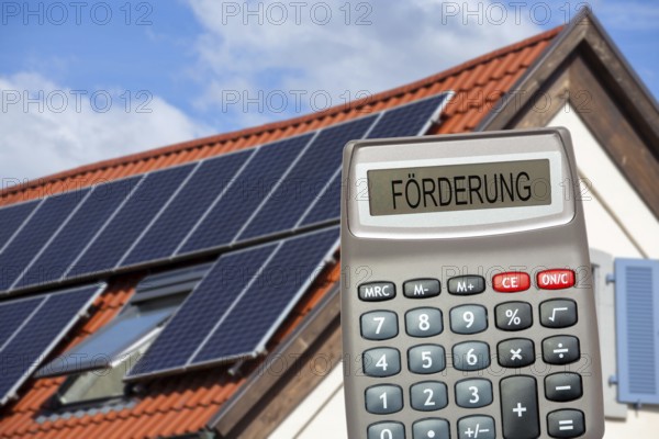 (photo montage) Pocket calculator with the inscription PROMOTION in front of a solar roof