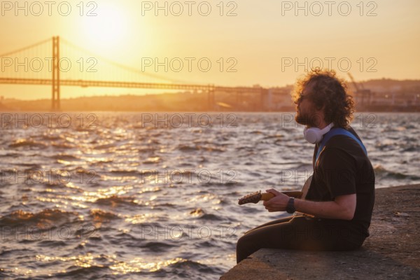 Hipster street musician in black playing electric guitar in the street on sunset