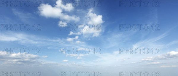 A tranquil sky filled with soft clouds under bright blue hues creates a peaceful daytime scene, ideal for relaxation and reflection