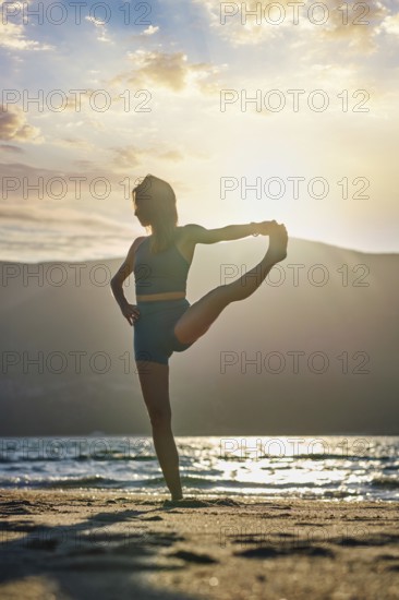 Yoga pose Utthita Hasta Padangusthasana Extended Hand-to-Big-Toe Pose at sunset on the beach