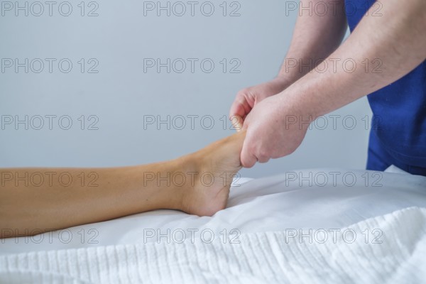 A woman enjoys a soothing foot and leg massage at a spa salon. The therapist uses oil for lymphatic drainage and relaxation