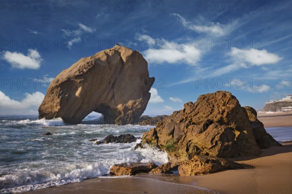 Penedo do Guincho rock at Praia da Santa Cruz as waves crash against the sandy shore during a colorful sunset