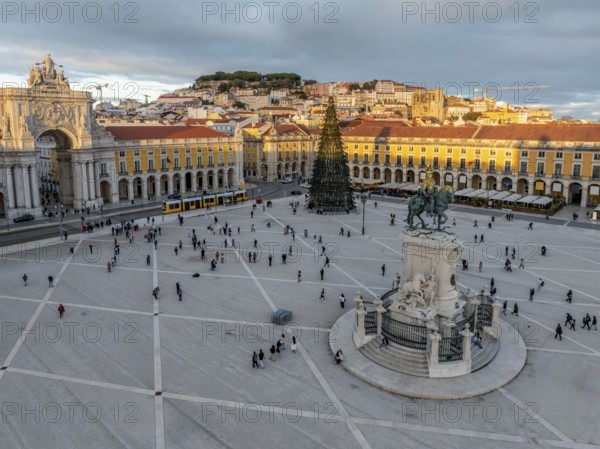 The scenic Praca do Comercio in Lisbon showcases a Christmas tree against the sunset sky, highlighting festive winter charm in the evening. Lisbon, Portugal