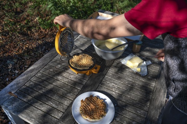 Preparation of waffles with a waffle iron on an outdoor garden table, Othenstorf, Mecklenburg-Western Pomerania, Germany