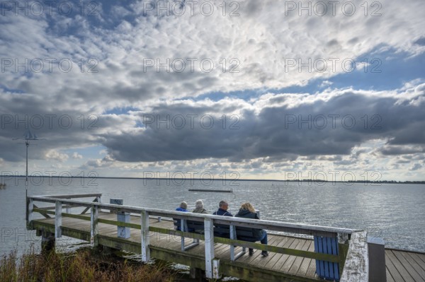 Tourists sitting on a bench at Wustrow harbour, DarÃŸ, Mecklenburg-Western Pomerania, Germany
