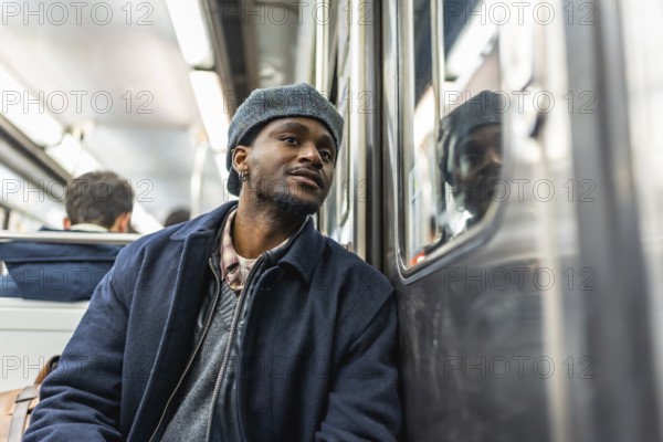 Young man sitting on a subway train, looking thoughtfully out the window during his daily commute, reflecting on the journey through the citys underground transit system