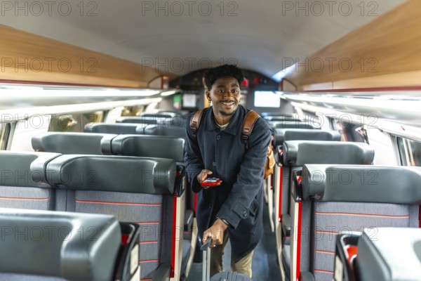 Young black man confidently walking through a train carriage, holding luggage and a mobile phone, representing modern travel, business journeys, and professional mobility