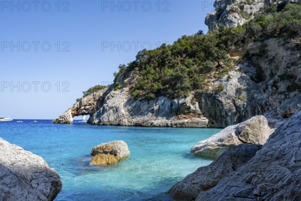 Light blue clear sea on a dream beach on Cala GoloritzÃ©, picturesque rocky coast, cliffs with rock arch, Golfo di Orosei, Baunei, Sardinia, Italy