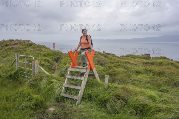 Crossing a fence while hiking to the lighthouse of, Sheepshead, County Cork, Ireland