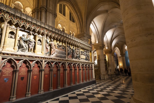 Notre dame cathedral interior with ornate gothic choir screen of detailed biblical sculptures, checkered marble floor and soaring arched columns in historic paris landmark
