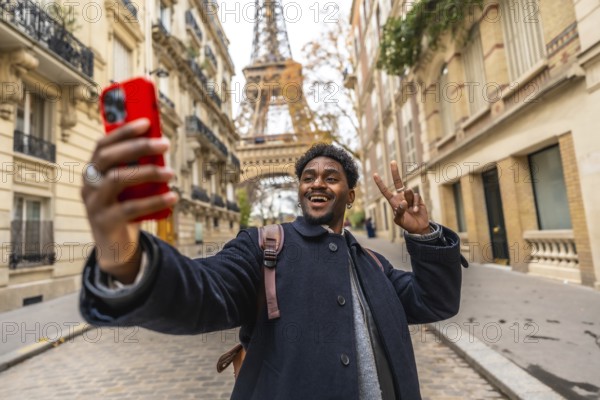Young man visiting paris, smiling and making a peace sign while taking a selfie with a smartphone, capturing a memorable moment with the iconic eiffel tower in the background