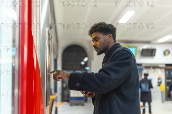 Young black man standing at a ticket machine in a modern train station, purchasing a ticket for his daily commute or a business trip, reflecting urban transport and travel concepts