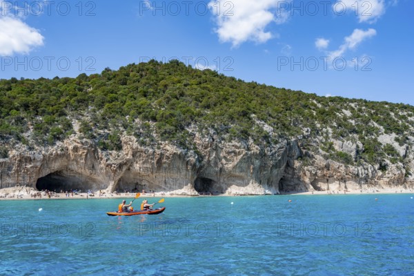 Kayakers in clear blue water, picturesque rocky coast, cliffs and Cala Luna beach, Golfo di Orosei, Baunei, Sardinia, Italy