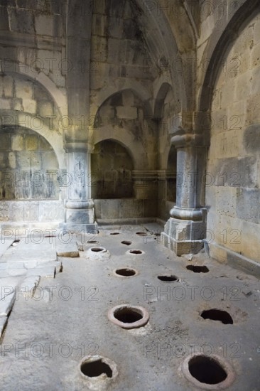Stone room with large floor holes and massive pillars surrounded by weathered walls, Haghpat Monastery, Haghpatavank, Haghpat town, UNESCO World Heritage Site, Lorikeet Province, Armenia