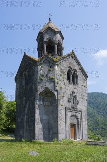 Small stone church with bell tower, surrounded by green nature and high-altitude mountains in the background, Haghpat Monastery, Haghpatavank, town of Haghpat, UNESCO World Heritage Site, Lorikeet Province, Armenia