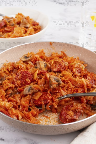Bigos, Polish dish bigos, on the table, pan with stewed meat, with cabbage, chorizo sausages, mushrooms, homemade, without people