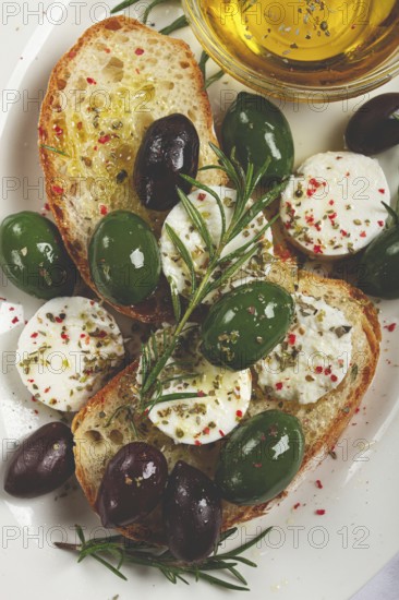 A plate with a snack, ciabatta bread with cheese and olives, olive oil, spices and herbs, top view, no people