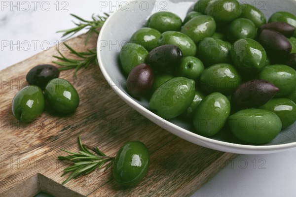 Chalkidiki olives, classic Greek green olives, in a bowl on a cutting board, top view, without people