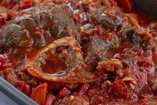 Ossobuco stew with vegetables, knuckle on the bone with new potatoes, in tomato sauce, homemade, top view, no people