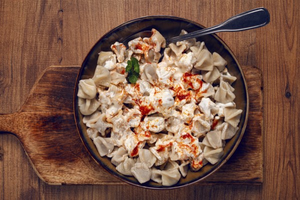 The dish features a generous serving of Turkish dumplings topped with velvety yogurt and a drizzle of spicy red sauce