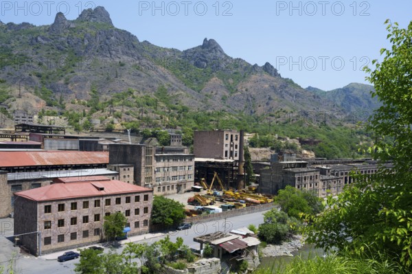 Industrial buildings nestled in a mountainous landscape under bright blue sky, former copper smelter, Alaverdi, Lorikeet province, Armenia
