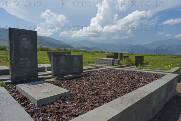 Tombstones in a cemetery with mountain landscape and blue sky in the background, grave decorated with obsidian, cemetery near Saint Nshan Church, Odsun, Odzun, Lorikeet province, Armenia