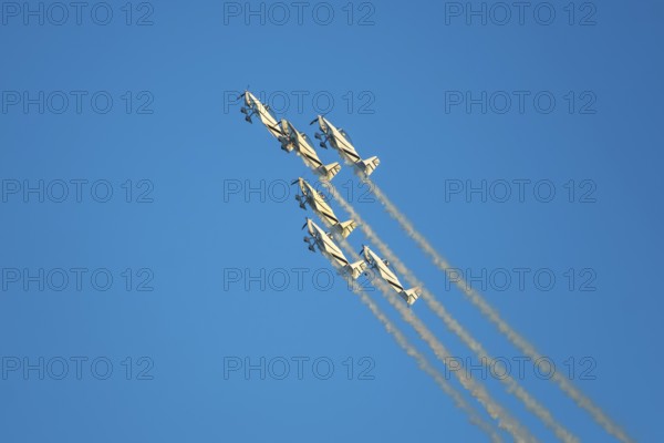 Stunt aerobatic planes performing stunts in blue sky with smoke trail. Concept of teamwork, collaboration, coordination, trust, precision, difficulty, challenge, speed, synergy