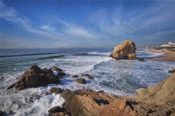 Penedo do Guincho, a large boulder rock arch at Praia da Santa Cruz, Portugal, with ocean waves and sandy beach