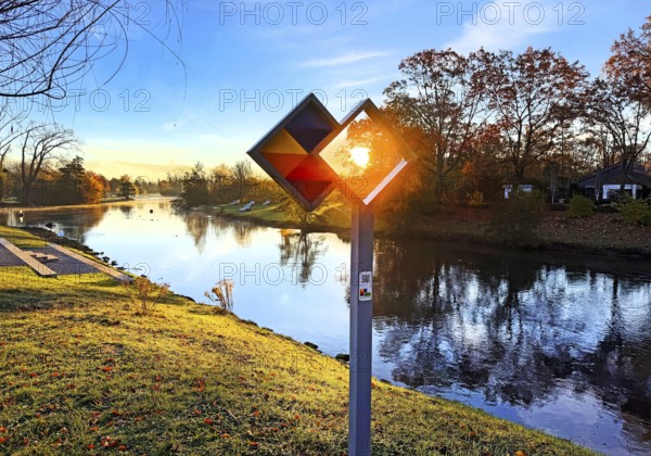 Sunrise over the Lippe river with the sign of the discovery route Wasser Wege Winkel, Lippeaue, Lippstadt, North Rhine-Westphalia, Germany