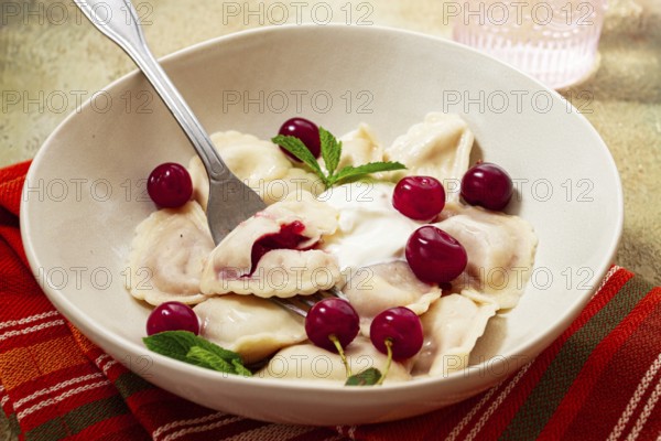 Traditional dumplings with cherries and yogurt, close-up, no people