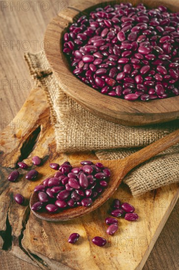 Red beans, laid out in a wooden bowl, on a chopping board, rustic style, covered with burlap, top view, close-up