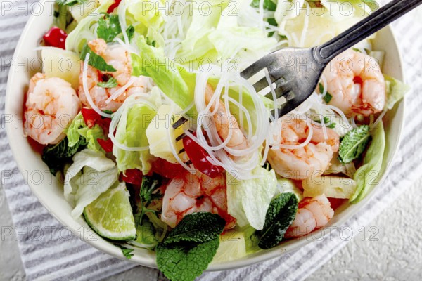 Thai salad with shrimp and rice noodles, pineapple slices, coriander and mint leaves, on a white plate, homemade, no people