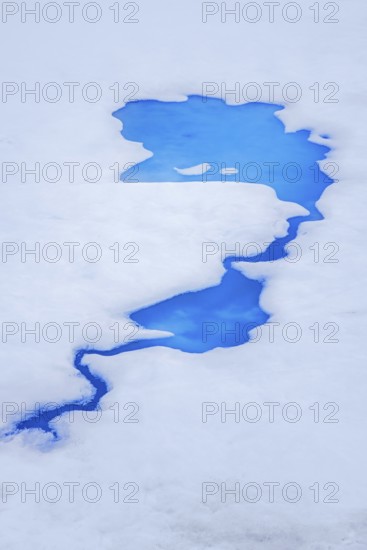 Aerial view over vivid blue water of meltpond / melt pond / meltwater pool on sea ice in the Arctic Ocean at Svalbard / Spitsbergen, Norway