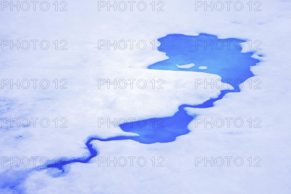 Aerial view over vivid blue water of meltpond / melt pond / meltwater pool on sea ice in the Arctic Ocean at Svalbard / Spitsbergen, Norway