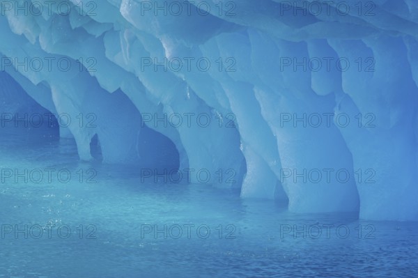 Dripping blue ice pattern from erosion by sea water on base of melting iceberg in the Arctic Ocean at Svalbard / Spitsbergen, Norway