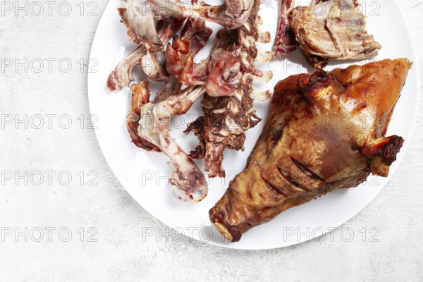 Roast pork head, with remnants of bones and meat, on a white platter, no people, close-up