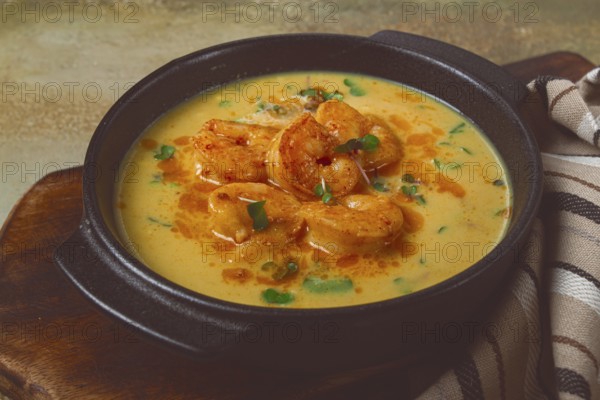 Creamy shrimp curry with spices, garnished with herbs, on a textured background, homemade, no people