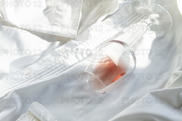 Glass, with pink wine, spilled on a white shirt, close-up, selective focus, no people, concept, top view