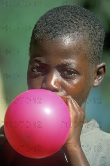 Local boy inflating balloon, Kande, Malawi, Africa, July 2000, vintage, retro, old, historic